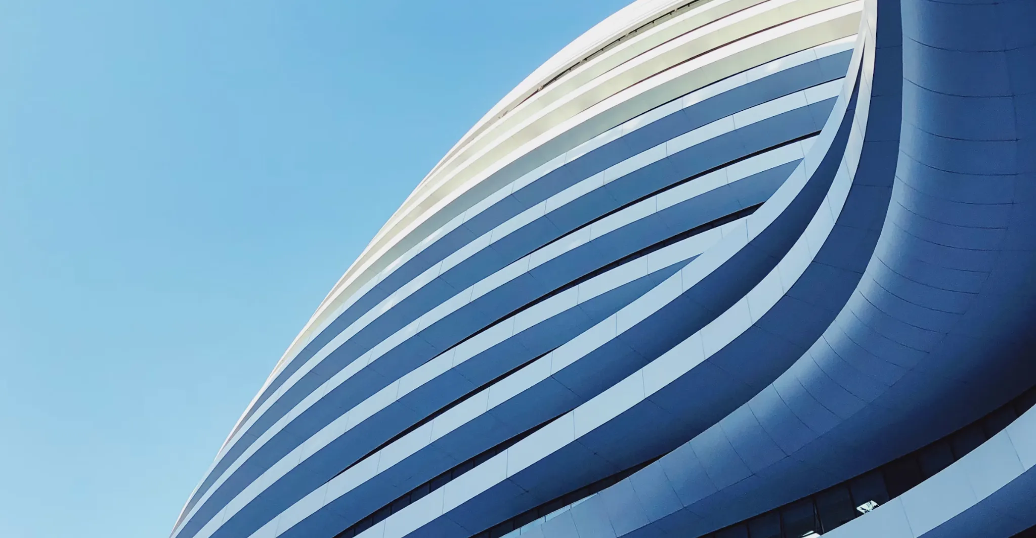 Curved contemporary building facade against a blue sky